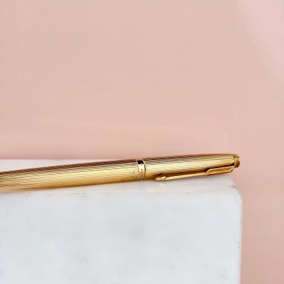 a gold fountain pen sitting on top of a marble block