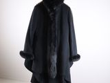 Un manteau noir à col de fourrure est suspendu à un cintre.
