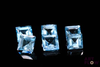 trois pierres de topaze bleue reposent sur une surface noire
