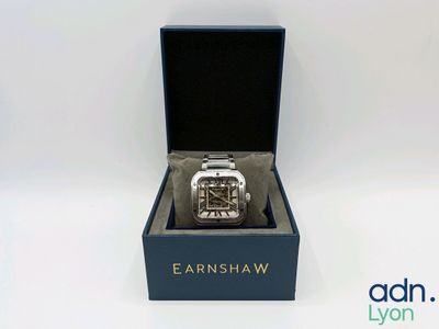 une montre posée dans un coffret sur une surface blanche