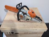 an orange and black chainsaw sitting on top of a wooden box