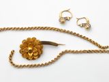 une photo d'un collier en or orné d'une fleur et d'une paire de boucles d'oreilles