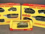 three boxed boxed toys of military vehicles on a gray surface
