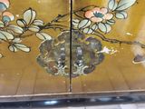 a close up of a gold painted cabinet with flowers on it