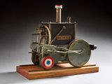 une petite maquette de machine à vapeur posée sur un socle en bois
