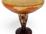 an orange and yellow glass bowl sitting on top of a wooden stand