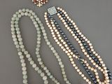un ensemble composé de trois colliers en perles et d'une broche