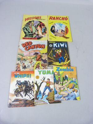 six bandes dessinées posées sur une table recouverte d'une nappe blanche