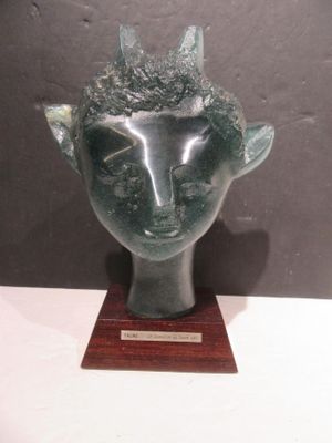 sculpture of a head with horns on a wooden base