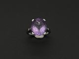 un gros plan d'une bague ornée d'une pierre violette sur un fond noir