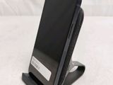 a black cell phone sitting on a stand on a table