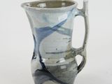 a blue and white vase with a handle on a white surface