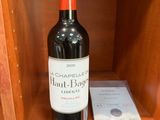 une bouteille de vin posée sur une étagère à côté d'un livre