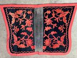 un vieux morceau de tissu noir et rouge orné de fleurs et d'oiseaux