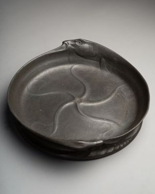 une assiette noire sur laquelle est représenté un oiseau, posée sur une table