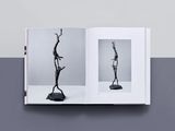 an open book with a black and white photo of two sculptures
