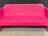 un banc en plastique rose posé sur un sol en béton