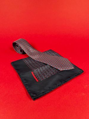 a red and black tie and a black wallet on a red background