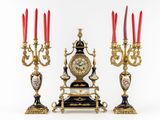 three candles and a clock sitting on a table