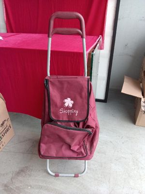a red shopping cart with a pink bag on it