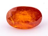 un gros plan d'un saphir orange de forme ovale posé sur une surface blanche