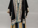 a woman ' s black and gold embroidered robe with blue trim