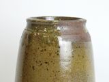 a brown and green vase sitting on a white surface