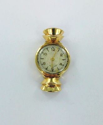 une horloge dorée posée sur une surface blanche, avec un fond blanc