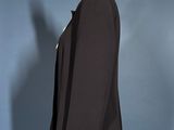 a black suit on a mannequin stand against a blue wall