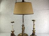 three candles are sitting on a table with a lamp on top of it