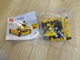 a yellow toy bulldozer sitting on a table next to a lego box