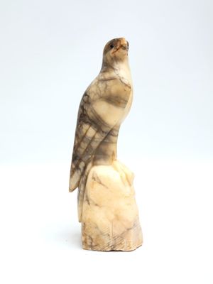 statue of a bird perched on a rock on a white background