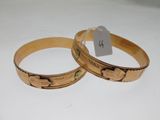 pair of gold tone bracelets with engraved designs on them