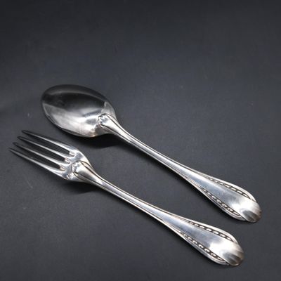 two silver spoons and a fork on a black surface