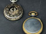 two silver and gold pocket watches sitting on a black surface
