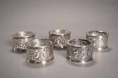 quatre serviettes en argent ornées de motifs, posées sur une table