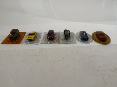 several toy cars are lined up on plastic trays on a white surface
