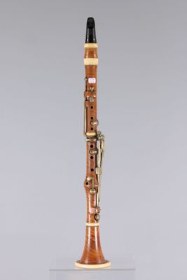 a close up of a clarinet on a clear surface with a gray background
