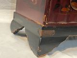 a red and black chest sitting on top of a white sheet