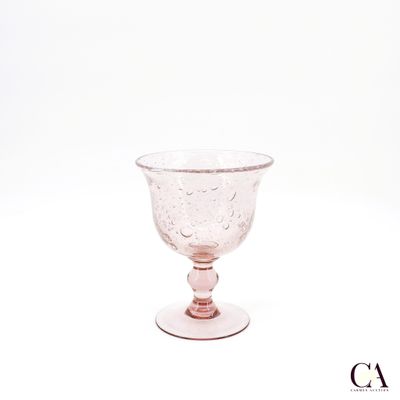 a pink glass cup sitting on top of a white table