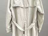 trench coat on a mannequin stand against a gray wall
