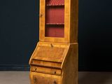 an old wooden bureau with a red glass door and drawers