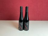 two bottles of wine sitting on a table with a red wall in the background