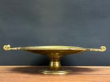 an antique brass plate with handles on a wooden table