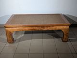 a small wooden table with a woven top on a tiled floor