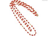 Collier de perles rouges et dorées sur fond blanc