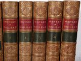several old books are lined up in a row on a shelf
