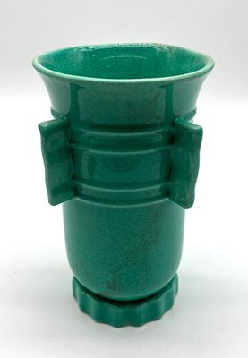 a green vase with a bow on the handle