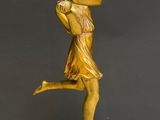 a gold statue of a woman holding a baseball bat on a marble base