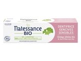 un dentifrice avec des feuilles de menthe sur fond blanc, accompagné d'une boîte de dentifrice